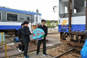 のと鉄道穴水駅構内検修庫にて自分たちでデザインしたヘッドマークを取り付けるため運ぶ３名